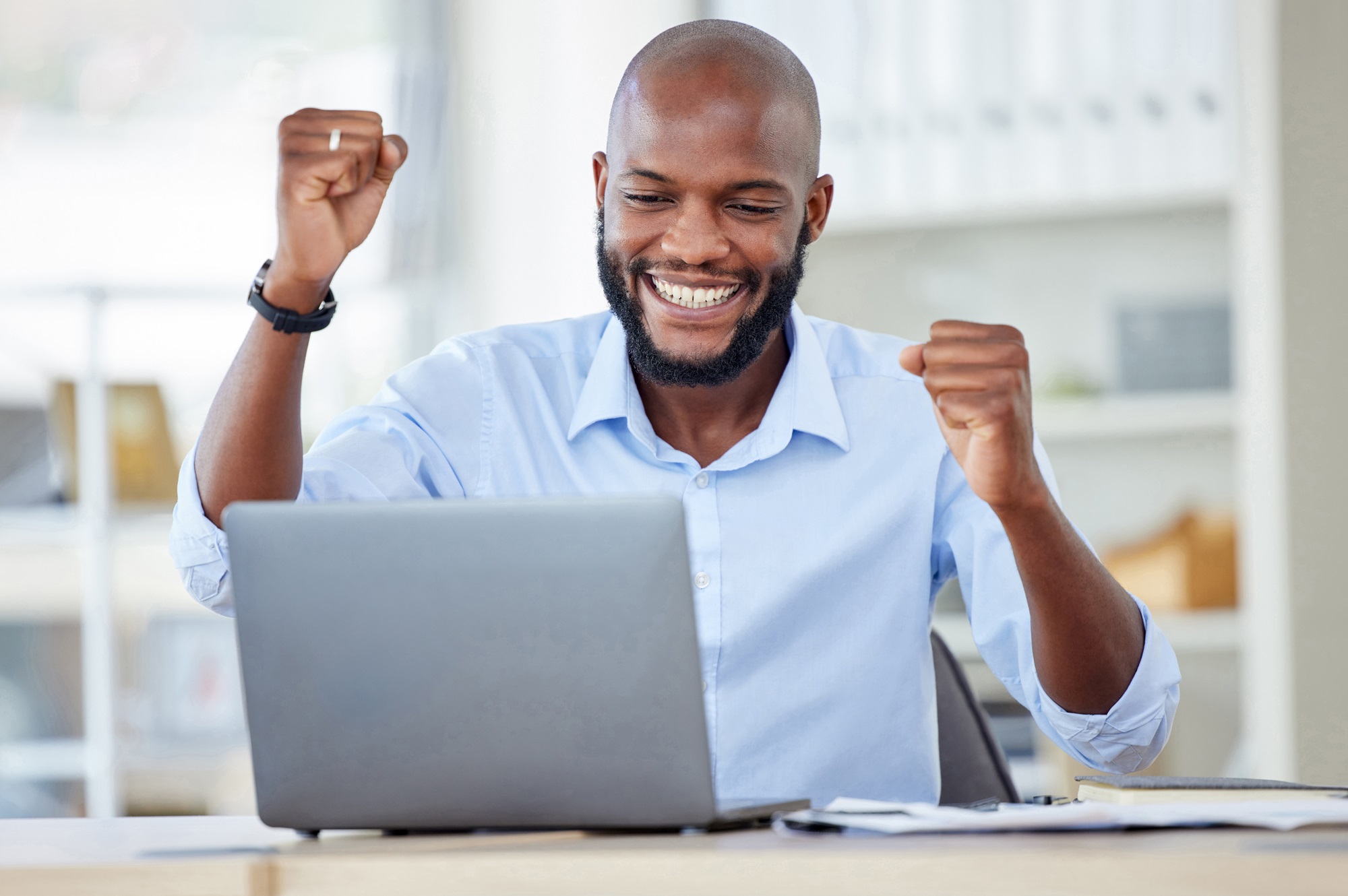A Man is Cheering in Front of a Laptop by Lifting his Both Fists