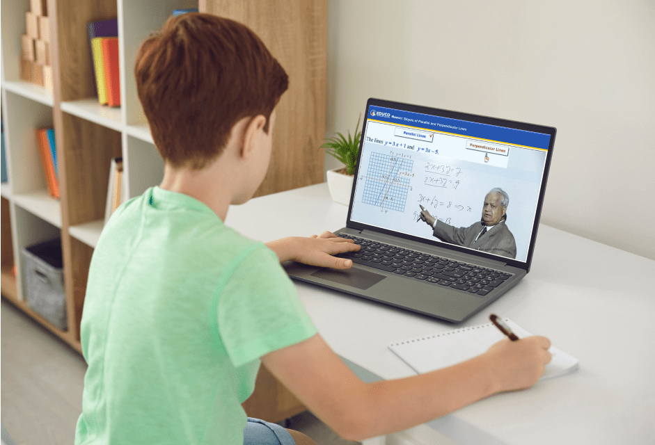 A Young Boy Sitting in front of a Computer Playing Educo Learning Center's Math Course Tutorial Video and is Taking Notes
