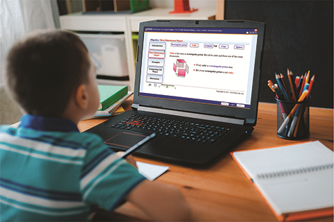 A Boy Taking Notes is Sitting in Front fg a Laptop Displaying Educo Learning Center's Online Courses